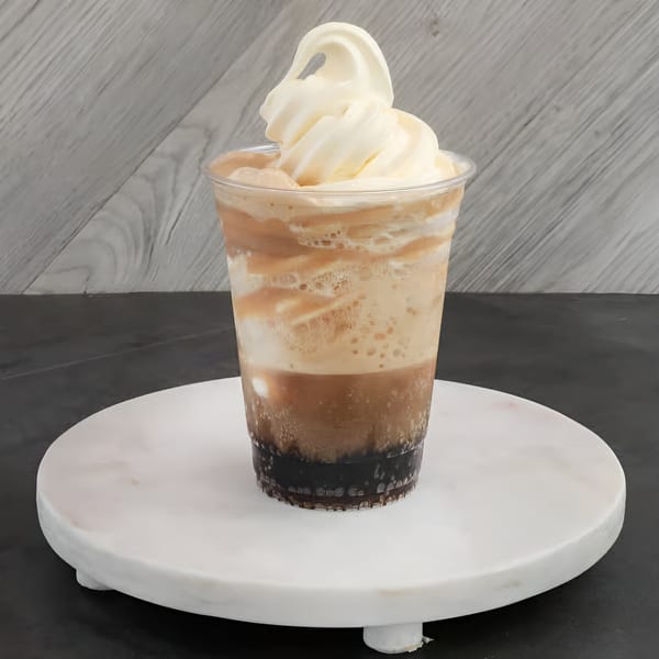 A Chilly Jilly'z root beer float with vanilla soft serve on a white marble stand.