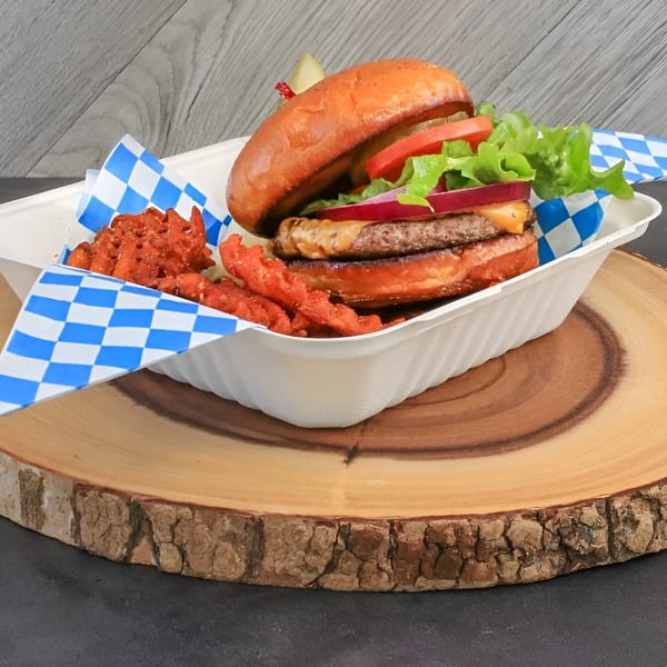 Chilly Jilly'z burger with lettuce, tomato, onion, and waffle fries in a takeout container on a wood slab.