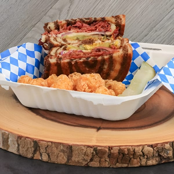 Chilly Jilly'z deli sandwich with pastrami, cheese, and pickles, served with popcorn shrimp and a pickle spear.